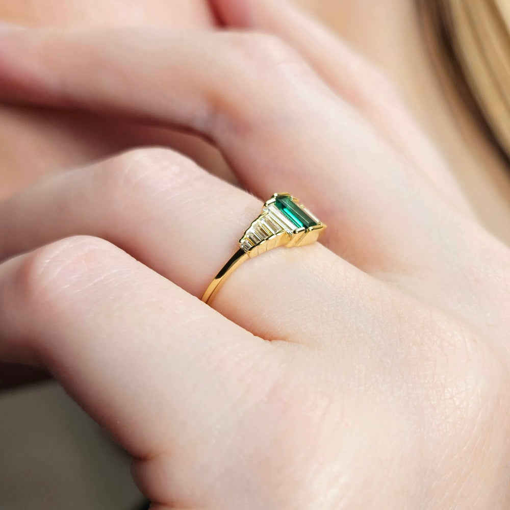 Gold ring with a green gemstone on a hand