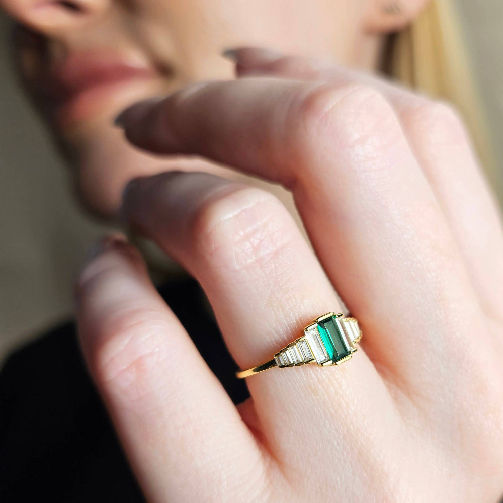 Gold ring with green gemstone on a person's finger